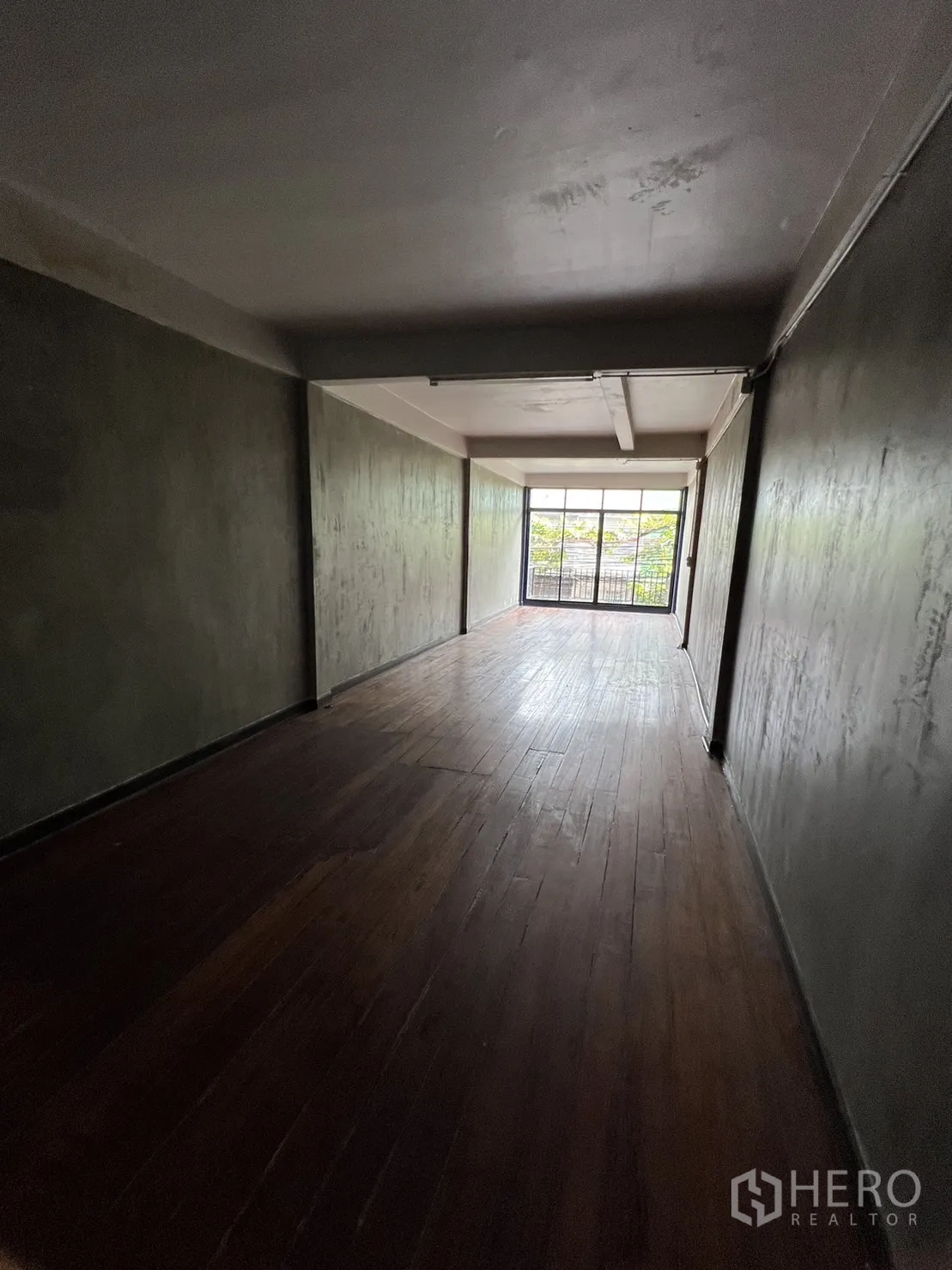 Shophouse for rent in Watthana, Bangkok - Deep living or studio space with dark wood floors and balcony doors.