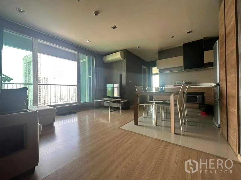 Condominium for sale in Phaya Thai, Bangkok - Open‑plan living and kitchen with floor‑to‑ceiling windows, balcony, and skyline view at Rhythm Phahol‑Ari.
