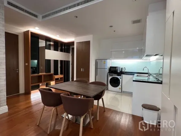 Condominium for rent in Khlong Toei, Bangkok - Open-plan dining area and modern white kitchen with built-in appliances and wood floors near BTS Phrom Phong.
