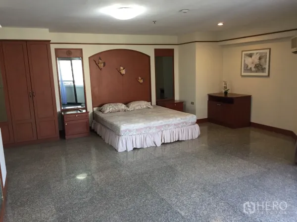 Condominium for rent in Watthana, Bangkok - Expansive master bedroom showing built-in wardrobes, twin mirrors, bedside tables and recessed lighting.