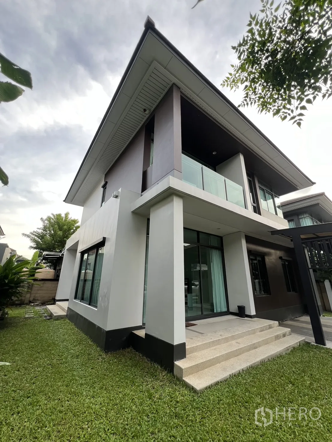 Detached House for rent in Bang Kapi, Bangkok - Corner exterior showing the balcony, large windows and green lawn.