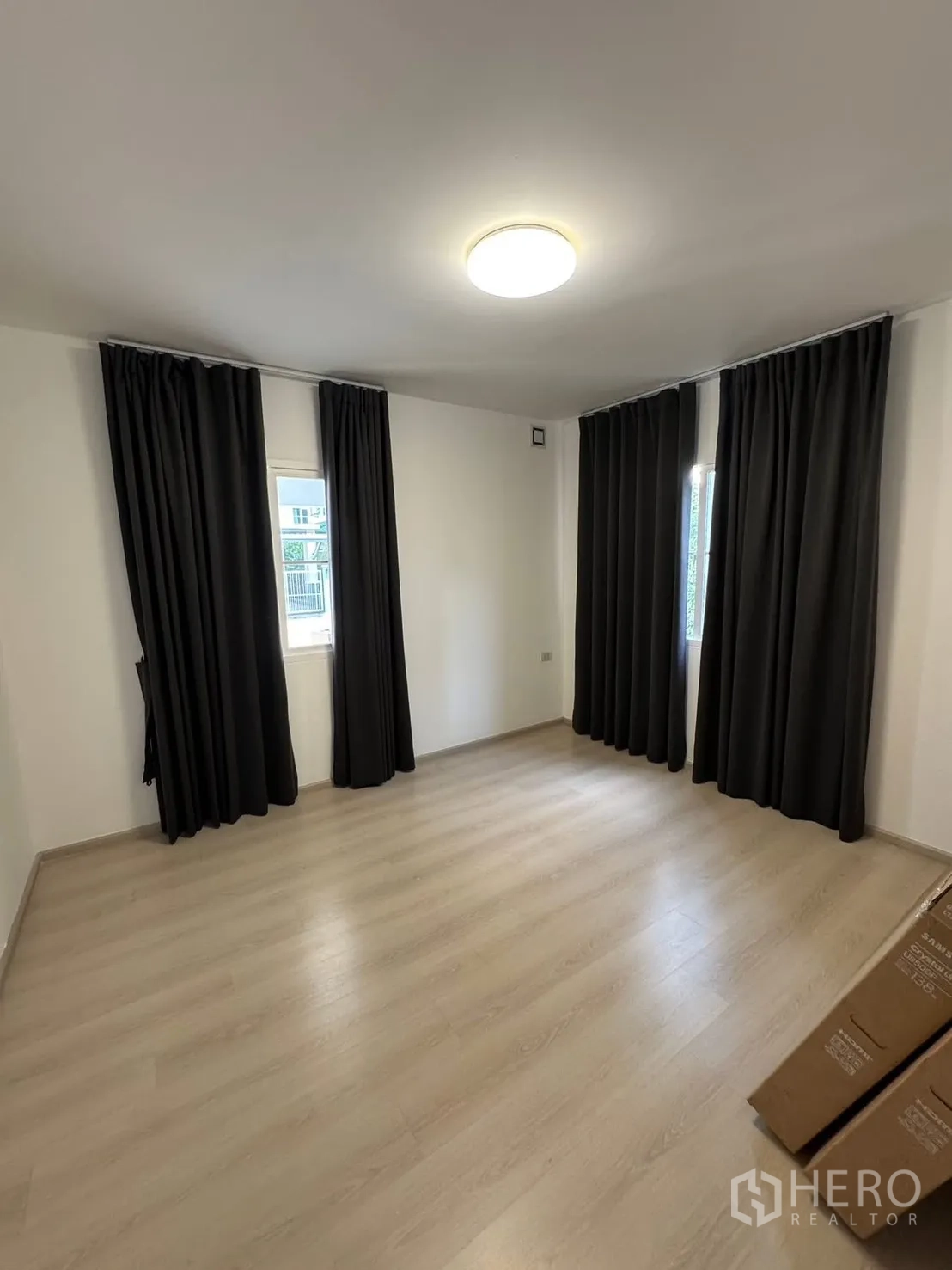Detached House for rent in Bang Phli, Samut Prakan - Empty corner bedroom with wood floors, blackout curtains, and windows.