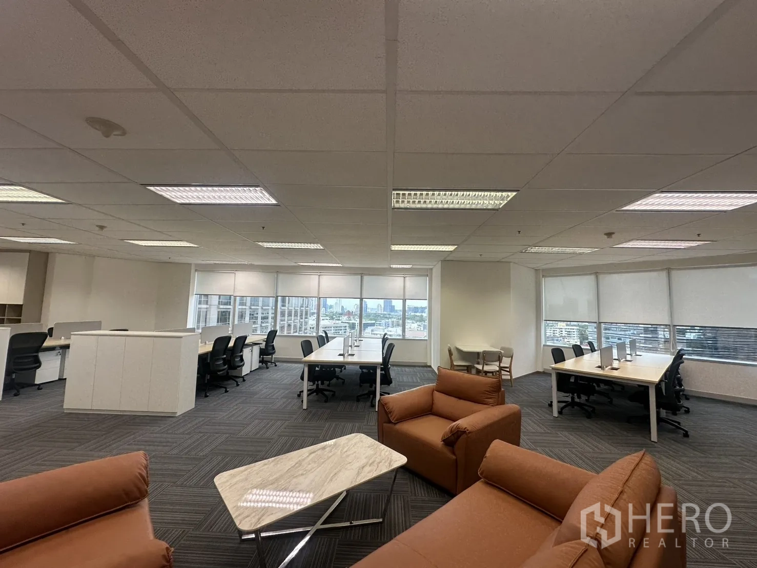Office Space for rent in Pathum Wan, Bangkok - Spacious open office with desks, lounge seating, and large windows with blinds.