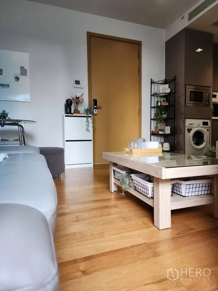 Condominium for rent in Watthana, Bangkok - Low-angle view of the lounge showing storage coffee table, door and kitchen entry.