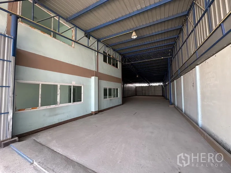 Warehouse for rent in Bueng Kum, Bangkok - Interior loading bay with high metal roof, side windows and smooth concrete floor.