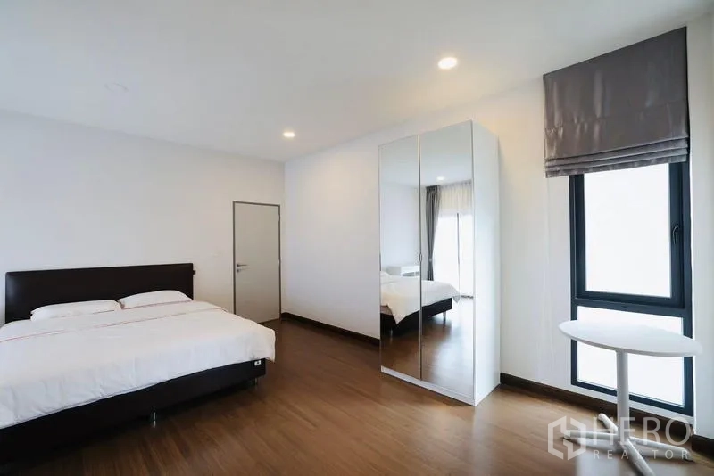 独立式住宅 出租在Bang Phli, Samut Prakan - 极简卧室，双人床、镜面衣柜与小圆桌。