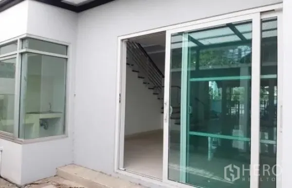 带办公室的家 出租在Wang Thonglang, Bangkok - 一层入口设大面积推拉玻璃门、转角窗与外部台阶。