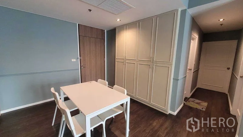 Condominium for rent in Khlong Toei, Bangkok - Dining area with a four-seat white table beside full-height storage cabinets in an open-plan condo.