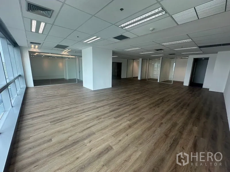 สำนักงาน ให้เช่า - พื้นที่สำนักงานแบบเปิด พื้นลายไม้ ฝ้าเพดานทีบาร์พร้อมไฟ และผนังกระจกกั้นห้องทำงาน.