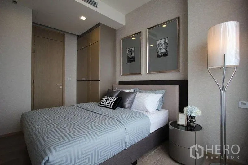 คอนโด ให้เช่าในWatthana, Bangkok - ห้องนอนอบอุ่น เตียงบุผ้า กรอบรูปติดผนัง และโคมไฟตั้งพื้น