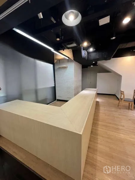 Retail Space for rent in Watthana, Bangkok - Long L-shaped counter beneath a black ceiling with spotlights in a contemporary retail unit.