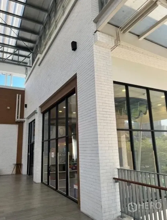 Retail Space for rent - Corner shopfront featuring floor-to-ceiling glazing and balcony railing in a mall setting.