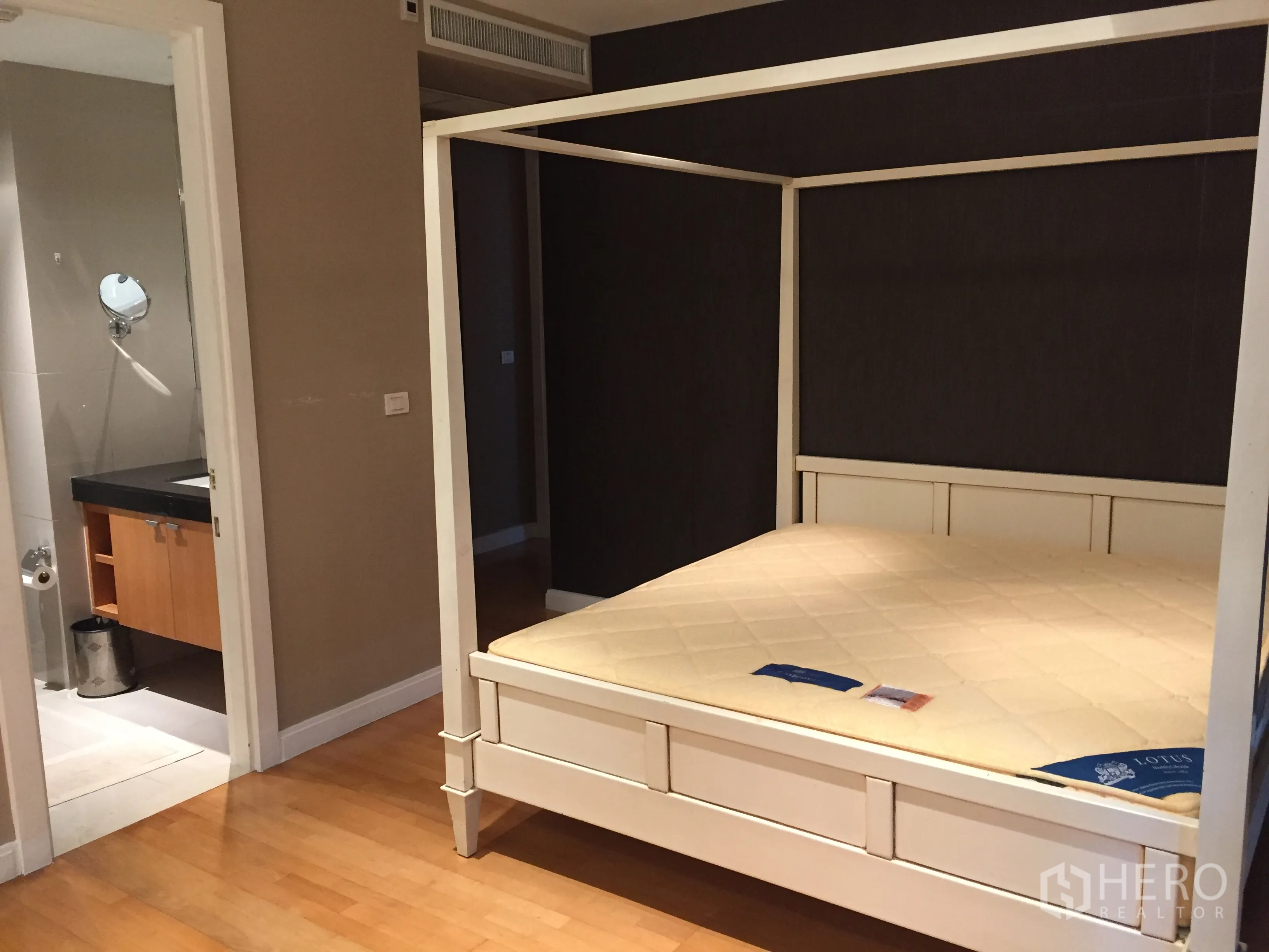 Condominium for rent in Pathum Wan, Bangkok - Second bedroom with four-poster frame and direct access to an ensuite bathroom.