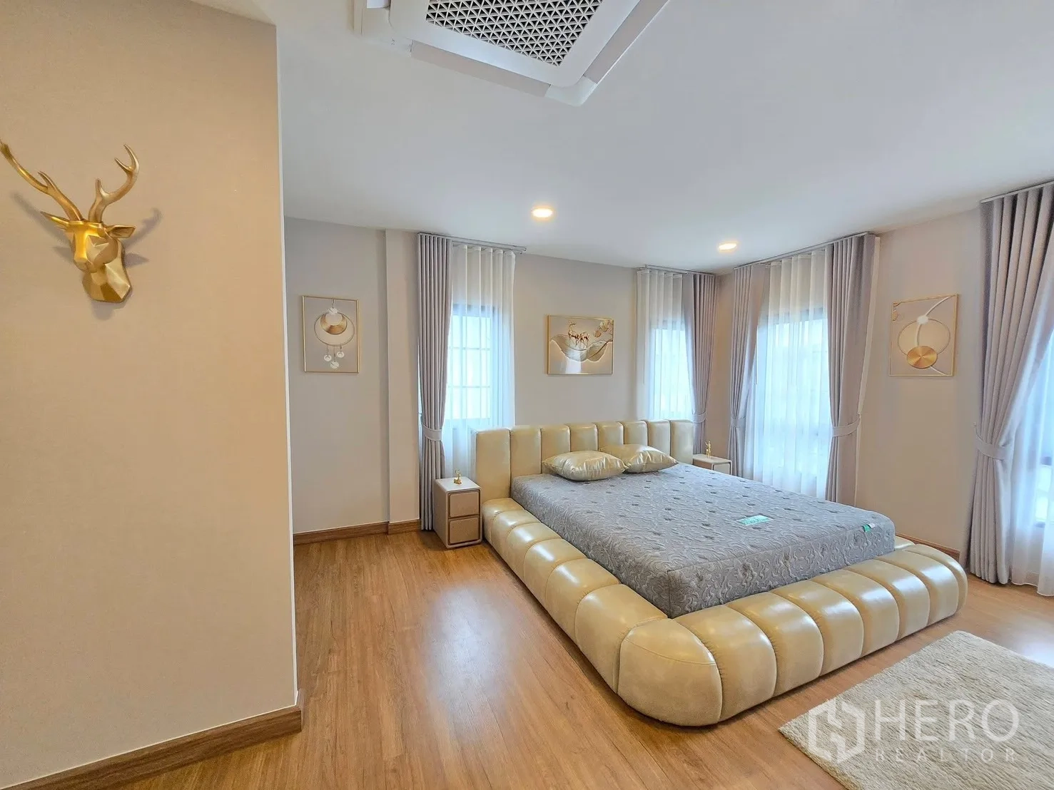 Detached House for rent in Bang Phli, Samut Prakan - Spacious master bedroom with upholstered platform bed, wood floors, and sheer curtains.
