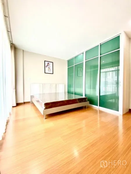 Townhouse for rent in Prawet, Bangkok - Spacious bedroom with green glass wardrobes, laminate floors and large windows.