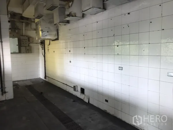 Retail Space for rent in Khlong Toei, Bangkok - Back-of-house tiled kitchen area with ventilation ducts and floor drain.