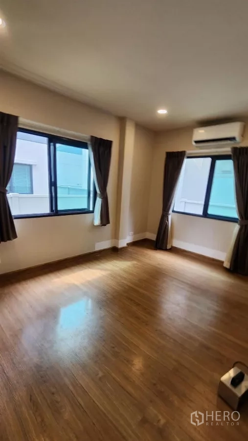 Detached House for rent in Bang Phli, Samut Prakan - Large secondary bedroom with wood floors, several windows and an air conditioner.