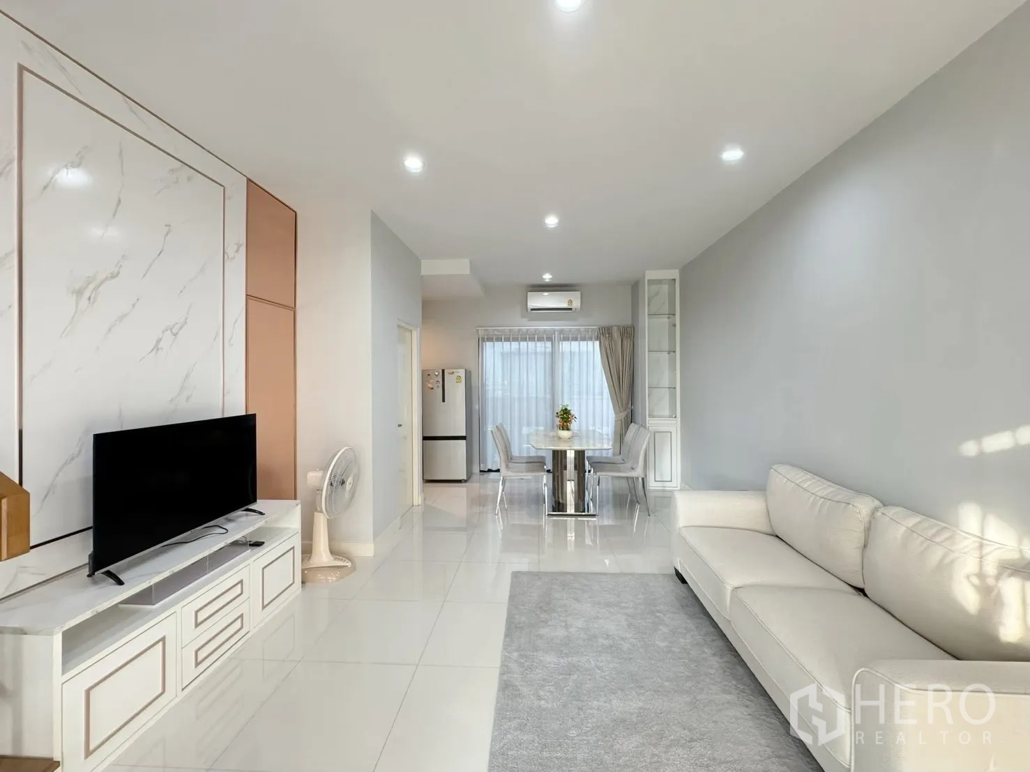 Townhouse for rent in Saphan Sung, Bangkok - Open-plan living and dining room with sofa, TV console and glossy tiled floors.
