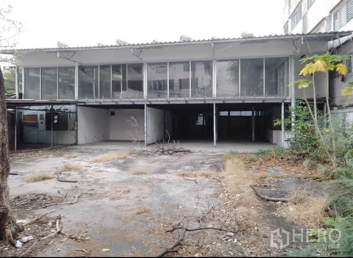 Warehouse for rent or sale in Bang Kho Laem, Bangkok - Front exterior of a two-storey warehouse featuring glass-panel upstairs offices and a wide concrete yard.