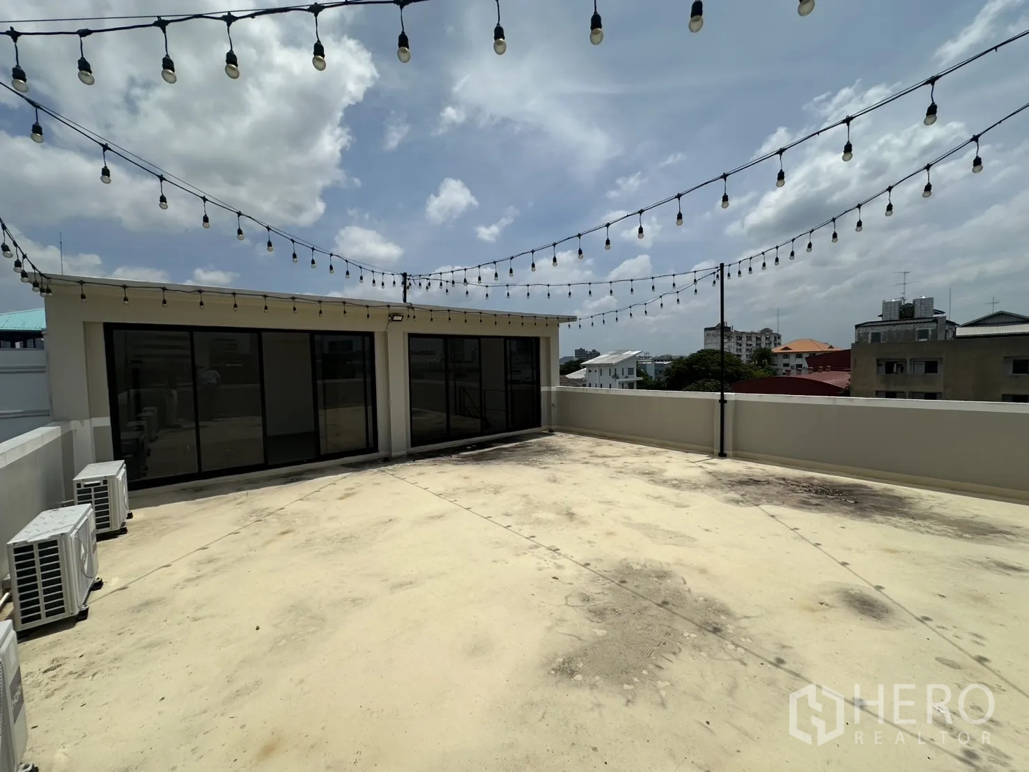 Home Office for rent or sale in Bang Na, Bangkok - Rooftop terrace with festoon lights, AC compressors and glass doors.