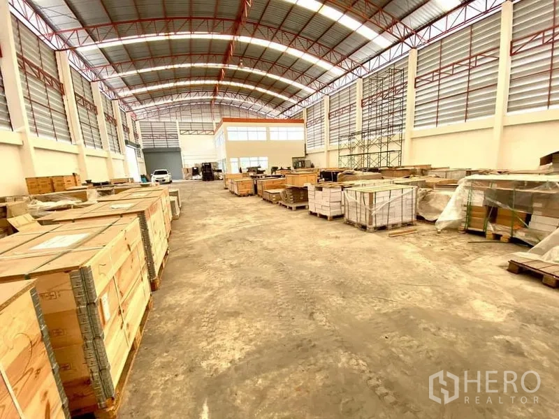 Warehouse for rent in Lam Luk Ka, Pathum Thani - High-clear warehouse hall with arched steel roof, crates and loading space.