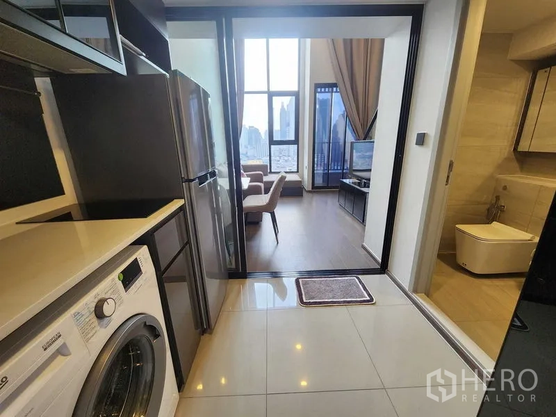 Condominium for rent - Compact kitchen with fridge and washer, sliding doors to the living room and adjacent bathroom.