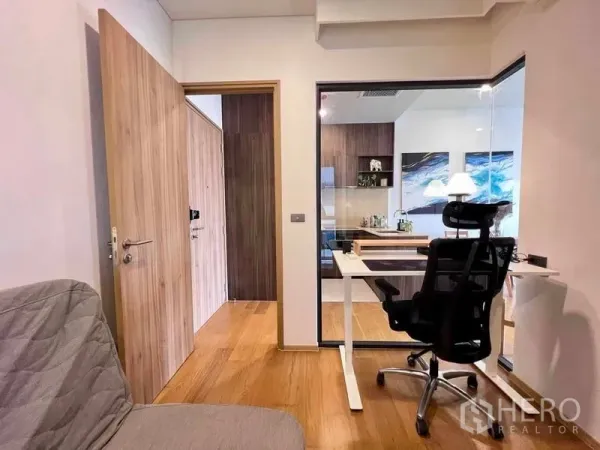 Condominium for rent - Home office nook with desk and ergonomic chair beside a glass partition and wood flooring.