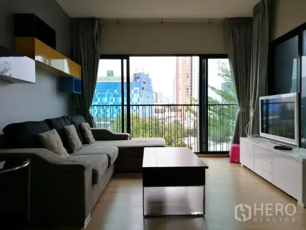คอนโด ให้เช่าในWatthana, Bangkok - มุมห้องนั่งเล่นอีกด้าน โซฟา ชั้นลอยตกแต่ง ผนังกระจกสูงจรดเพดาน และทิวทัศน์เมืองจากระเบียง