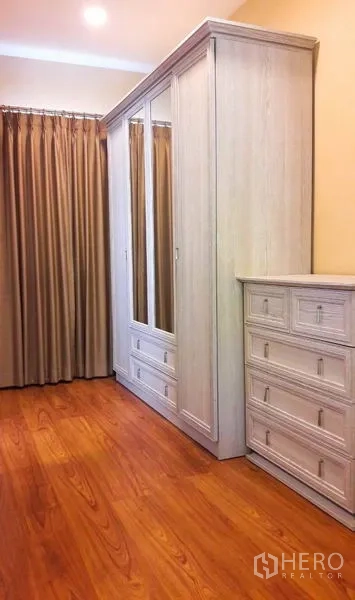 Detached House for rent or sale in Bang Yai, Nonthaburi - Built-in wardrobe and dresser in a walk-in closet with wood flooring and curtains.