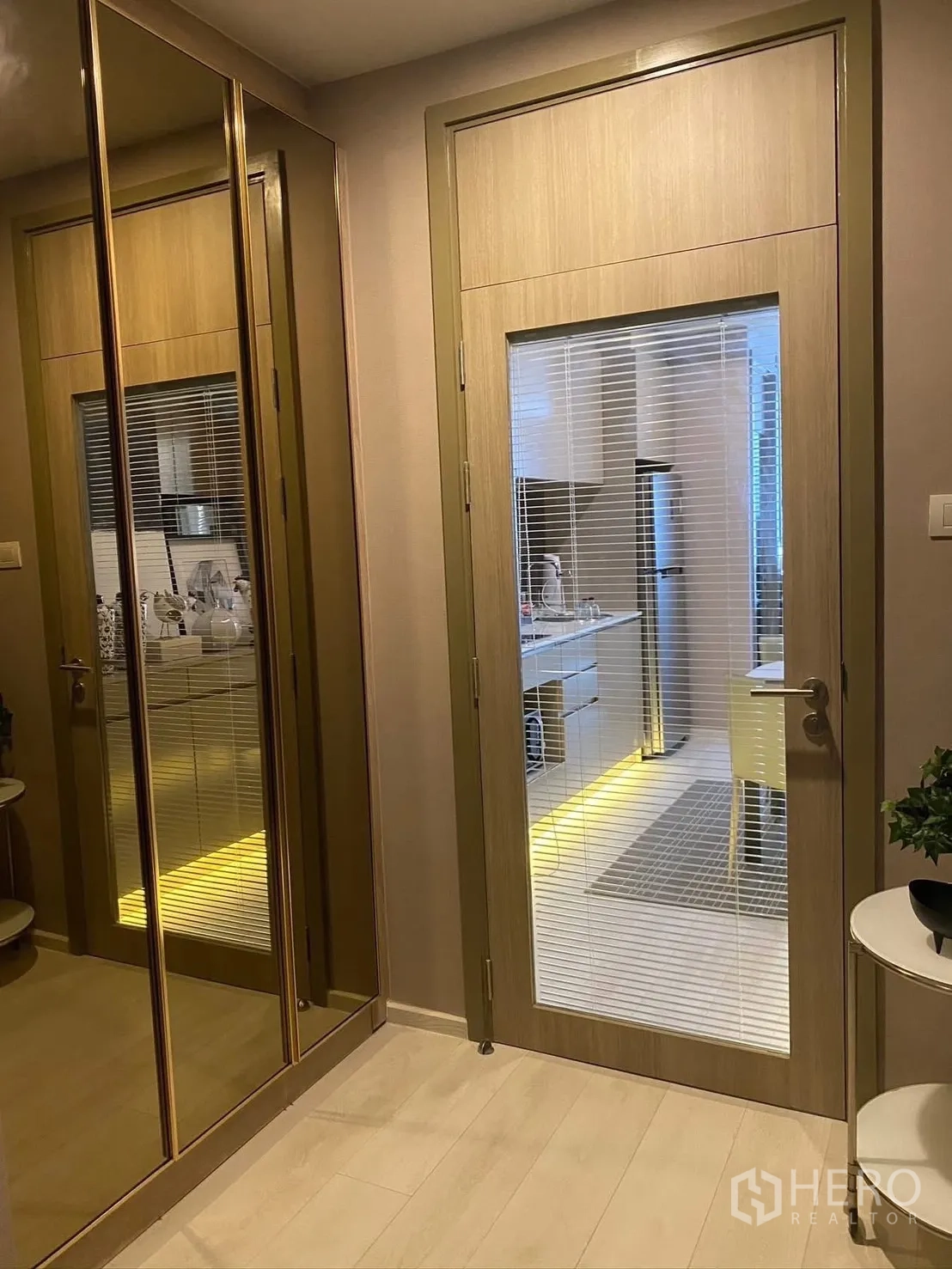 公寓 for rent in Pathum Wan, Bangkok - 入口走廊设有镜面衣柜与玻璃门，可见带暖色灯带的厨房。