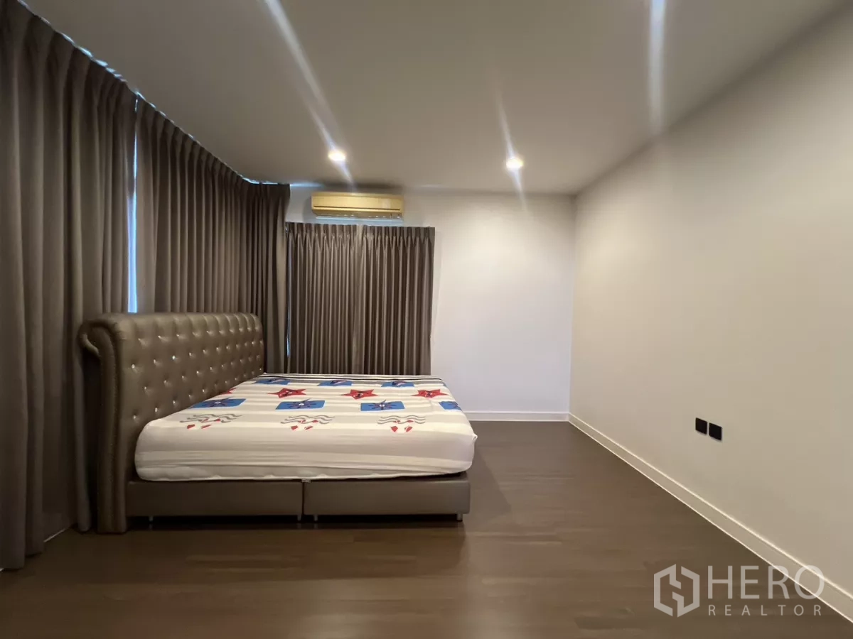 Detached House for rent in Bang Kapi, Bangkok - Large master bedroom with upholstered bed and full-height blackout curtains.