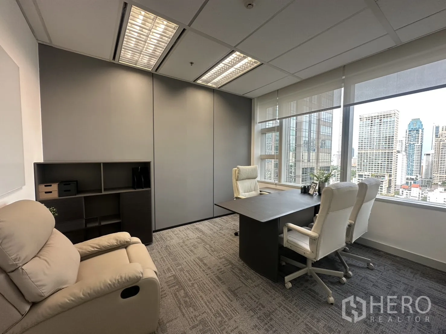 办公室 for rent in Pathum Wan, Bangkok - 主管办公室设有大窗、城市景观、白色座椅与书柜，地面为地毯。