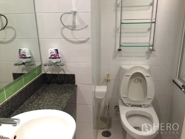 Condominium for rent or sale in Khlong Toei, Bangkok - Compact bathroom with toilet, sink, granite vanity and glass shelving.
