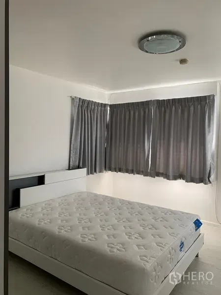 公寓 出租或出售在Watthana, Bangkok - 明亮卧室，双人床、灰色窗帘与转角窗，曼谷公寓内景。