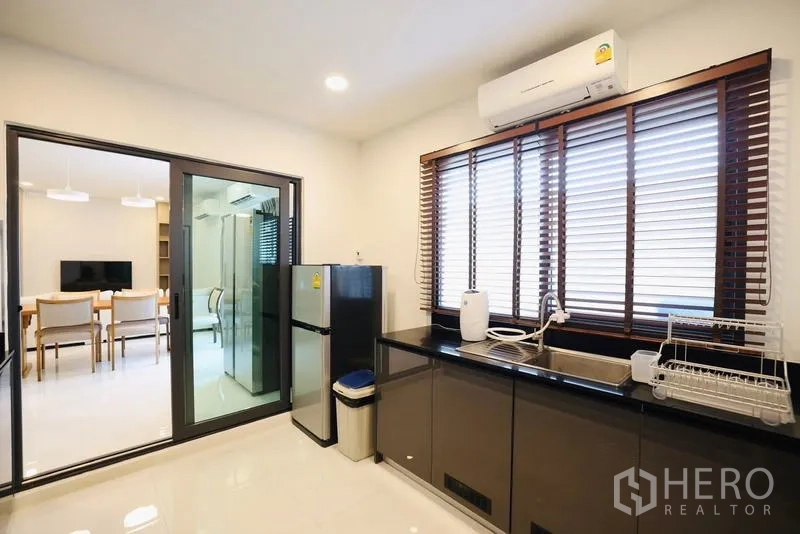独立式住宅 出租在Bang Phli, Samut Prakan - 封闭式厨房，黑色台面、百叶窗与不锈钢冰箱。