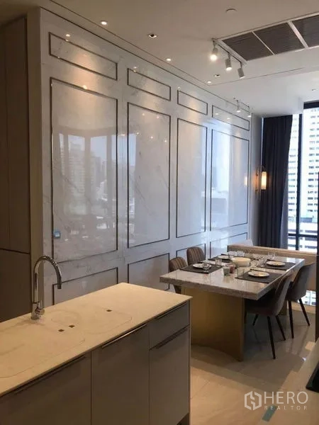 公寓 出租在Bang Rak, Bangkok - 开放式厨房与餐区，带大理石中岛、装饰墙面和城市景致。