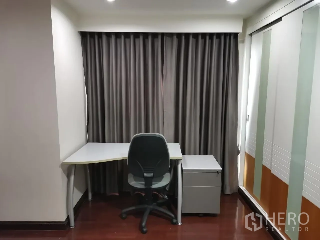 Condominium for rent in Phaya Thai, Bangkok - Compact home office with corner desk, task chair and full-length blackout curtains.