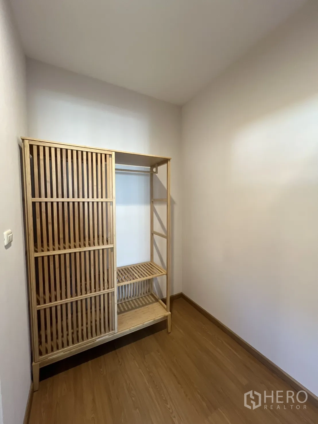 Detached House for rent in Bang Kapi, Bangkok - Small room with a wooden open wardrobe and wood floors.