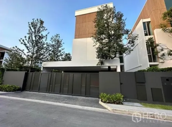 独立式住宅 出租 - 曼谷沙攀颂现代独栋别墅外观，高隐私大门与绿树。