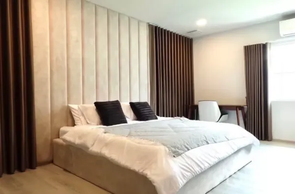 独立式住宅 出租在Bang Phli, Samut Prakan - 宽敞主卧，软包背景墙、特大床、书桌与遮光窗帘。