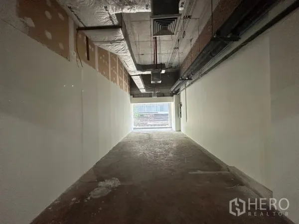 Retail Space for rent in Watthana, Bangkok - Unfinished retail interior with exposed ceiling ducts, white walls, concrete floor, and daylight from the rear window.