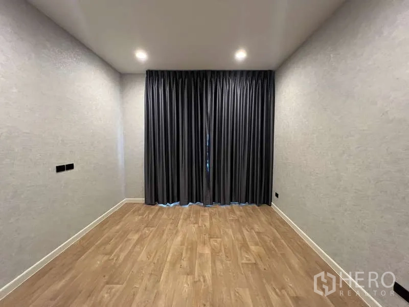 Detached House for rent in Bang Kapi, Bangkok - Empty multipurpose room with wood flooring and dark curtains.