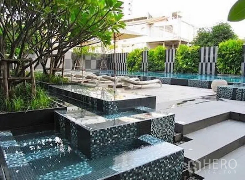 公寓 出售在Watthana, Bangkok - 度假风泳池平台，阶梯式马赛克水景与躺椅。