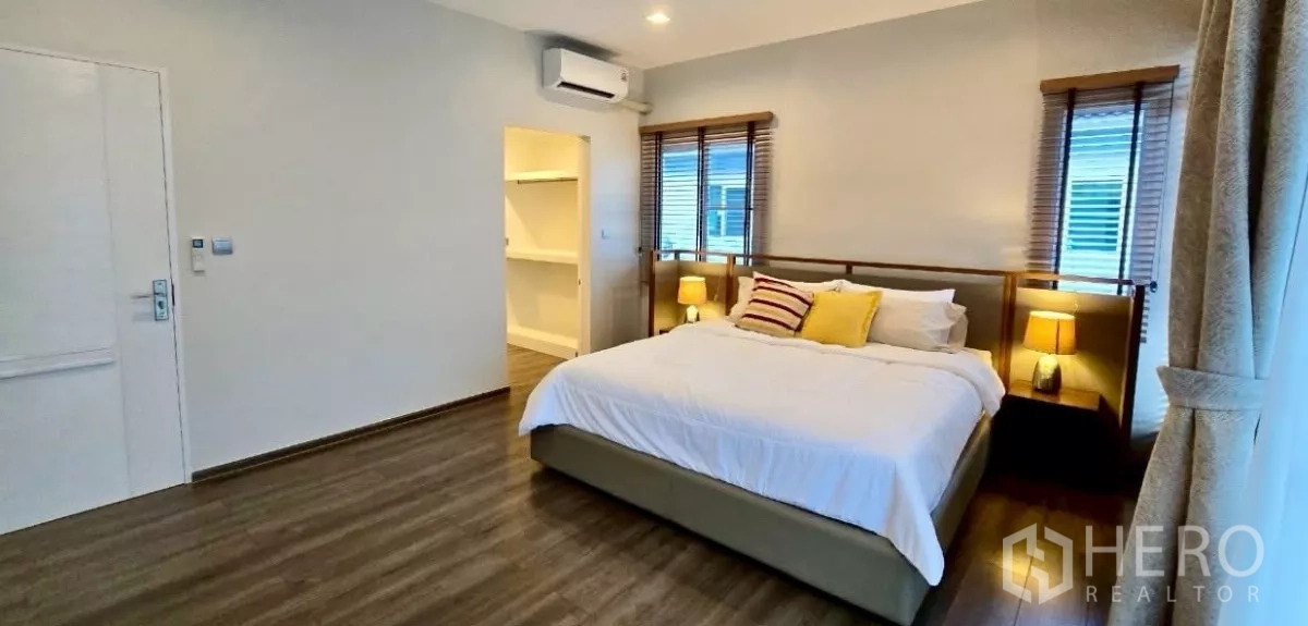 独立式住宅 出租在Samut Prakan - 主卧一角，通往步入式衣帽间，木纹地板