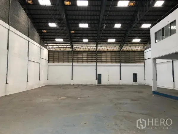 Warehouse for rent in Bang Phli, Samut Prakan - Open warehouse floor with high clearance, bright roof panels, and side access doors.