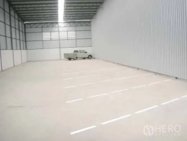 Warehouse for rent in Phra Pradaeng, Samut Prakan - Spacious empty warehouse interior with high metal roof, bright linear lighting and smooth concrete floor.