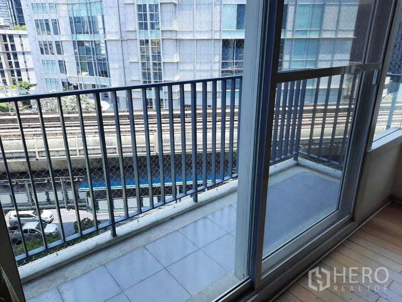 Condominium for rent in Khlong Toei, Bangkok - Small balcony with metal railing overlooking BTS tracks and city buildings.