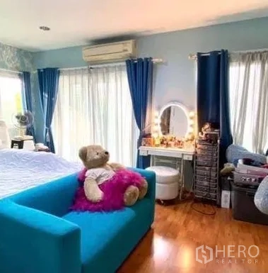 独立式住宅 出售在Khan Na Yao, Bangkok - 明亮主卧，蓝色沙发、梳妆台、木地板，大窗配蓝色窗帘
