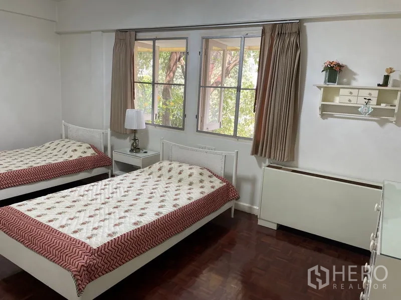 Apartment for rent in Watthana, Bangkok - Twin bedroom with two single beds, a bedside table and large windows.