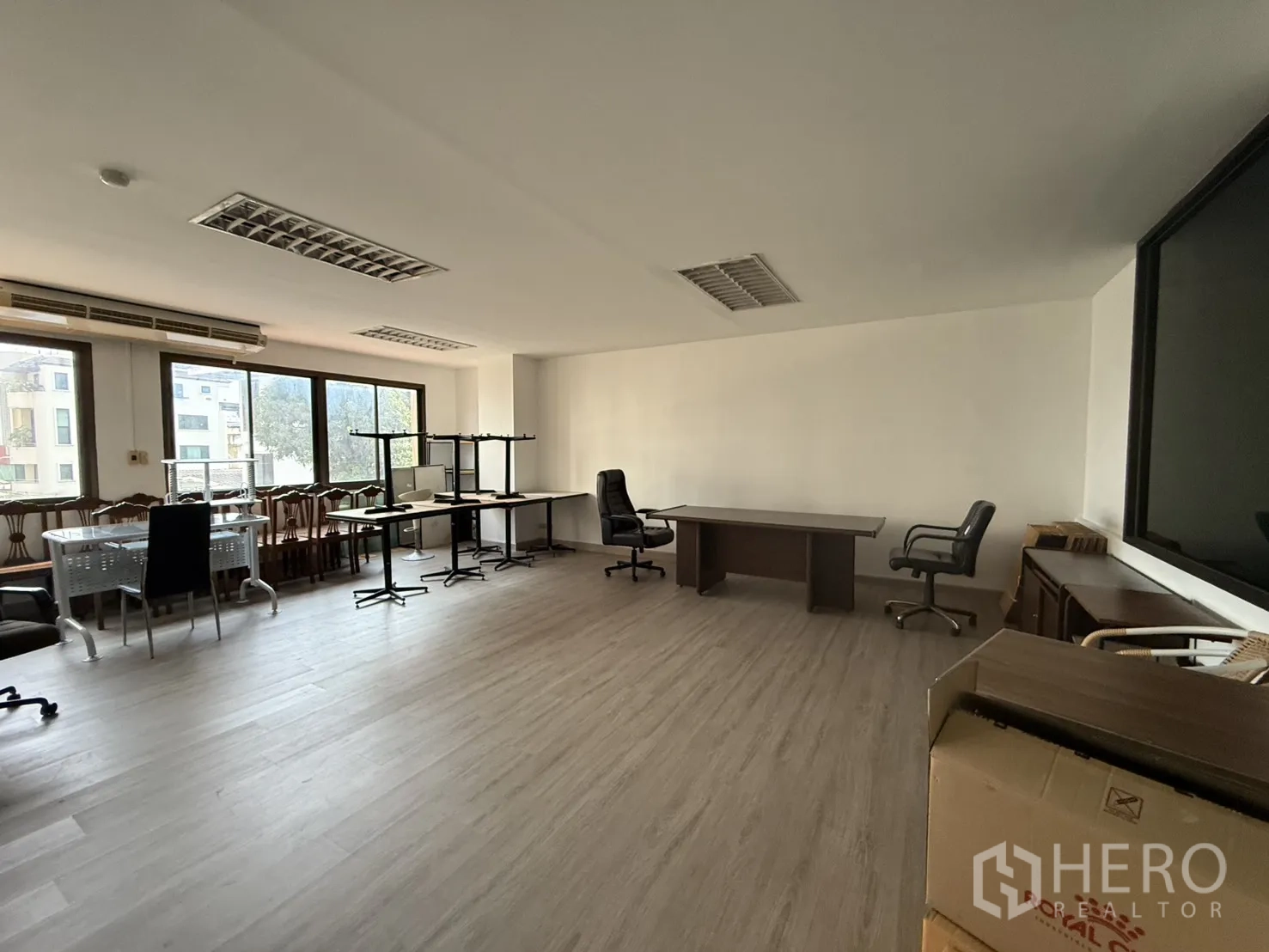 办公空间 for rent in Sathon, Bangkok - 采光充足的工作区，长桌与转椅搭配木纹地面，靠窗可见城市景致。
